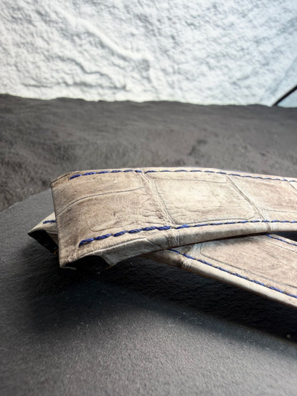 Close-up of a textured fabric with blue stitching on a gray surface